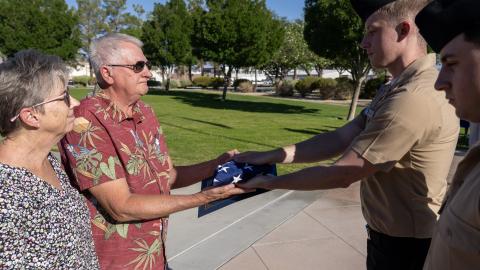 Harlan Kooima, (center) director of research and development at Naval Air Warfare Center Weapons Division alongside his wife, Kim, is presented with a flag during a ceremony celebrating his retirement from federal service on July 31 in China Lake, Calif. 