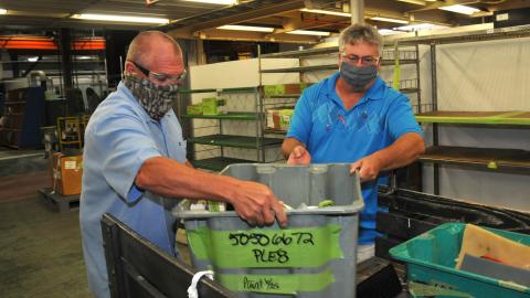 Supervisors work together to load parts to transport for processing.