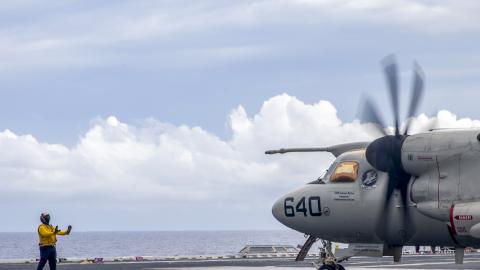 A Sailor assigned to USS Gerald R. Ford (CVN 78) signals "move back" to an E-2D Tracer.