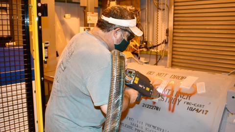 Worker users laser to clean container
