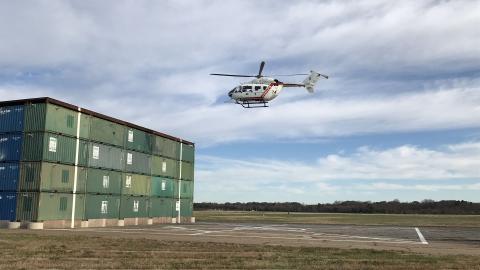 A U.S. Naval Test Pilot School (USNTPS) UH-72A Lakota hovers near the Elevated Fixed Platform as part of a test program developed by USNTPS rotary wing instructors John Tritschler and John Holder to evaluate the hover performance of helicopters near obstacles and inside confined areas.