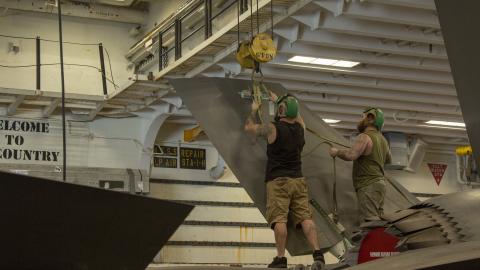 Two aircraft mechanics perform repairs on F-35B