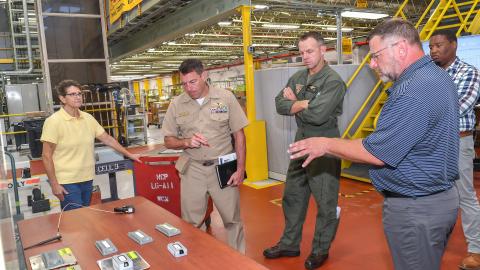 Jarred Burr, left, an electrical engineering technician at Fleet Readiness Center East (FRCE), briefs FRCE Commanding Officer Capt. James Belmont on radio frequency identification (RFID) technology tags tested and evaluated at the depot. FRCE recently demonstrated a successful proof of concept for a digital tracking system incorporating RFID and other technology. Depot officials say the system could boost efficiency and accountability within the depot’s workforce. 