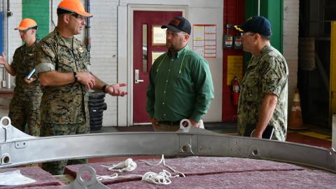 Maj. Gen. Scott F. Benedict, commanding general of 2nd Marine Aircraft Wing (MAW), left, discusses MV-22 stow rings with  Fleet Readiness Center East (FRCE) Commanding Officer Capt. James Belmont  and FRCE V-22 Branch Head Andrew Rock during an Aug. 30 tour of the depot by 2nd MAW leadership. 