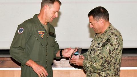 Navy captain passes award statuette to Marine lieutenant colonel