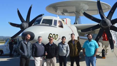 Group of people standing in front of E-2D aircraft.