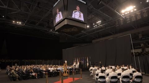 People attend a Navy change of command ceremony in an athletic arena. 