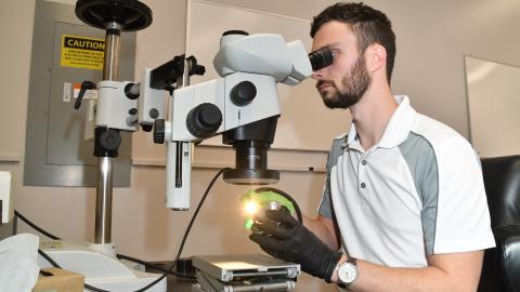 Latane Mason, a materials engineer at Fleet Readiness Center East’s (FRCE) Materials Engineering Division, examines a fractured surface using a stereo microscope. The Materials Engineering Division utilizes state of the art laboratory equipment to perform research, testing and evaluation activities as well as to develop and continually improve the processes in use within FRCE.