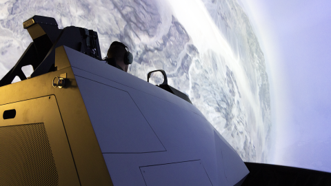A cockpit sits in a domed simulator that with a global display.