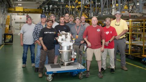 Artisans at Fleet Readiness Center East’s (FRCE) Engine Driven Compressor and Gas Turbine shop stand for a group photo with a freshly overhauled auxiliary power unit for the F/A-18E/F Super Hornet. FRCE recently achieved a significant production milestone by eliminating high-priority backorders for auxiliary power units used in the Super Hornet, bolstering the platform’s mission readiness. 