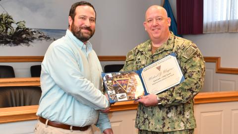 Man in military uniform stands with man in blue shirt 
