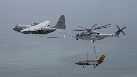 C-130 plane aerial refuels a CH-53K helicopter while carrying an F-35 airframe in the sky