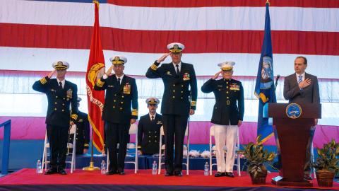 Sailors stand on a stage saluting