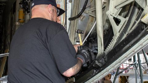 man in black shirt works on inside of aircraft