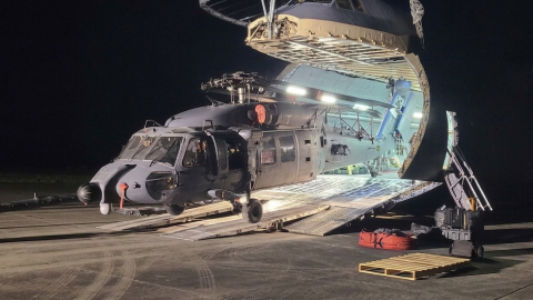 HH-60W helicopter coming out of a C-5 aircraft nose at night 
