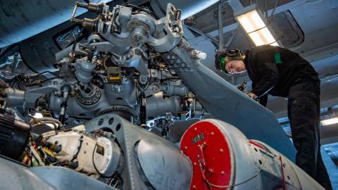 A Sailor inspects rotor gear for corrosion aboard the MH-60S Seahawk Helicopter.