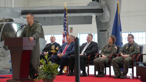 The HX-21 commander speaks at a podium during a change of command ceremony.