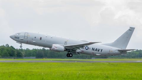 P-8A flies away with green grass in the foregound