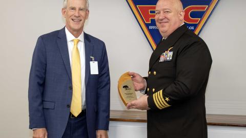 Sailor poses for award photo with man in blue suit