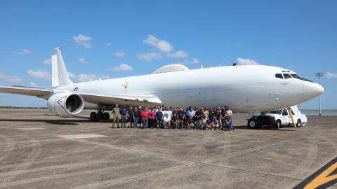 Team members pose with E-6B Mercury on flight line. 