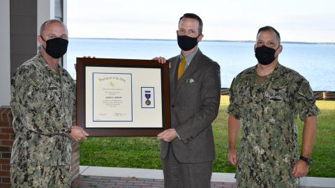 Three men pose for award presentation photo