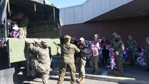 Volunteers work with Sailors from Joint Base McGuire Dix Lakehurst to fill trucks with toys for the annual Toys for Tots drive.