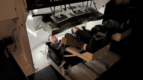 Two Navy pilots operate an Orion spacecraft display monitor.